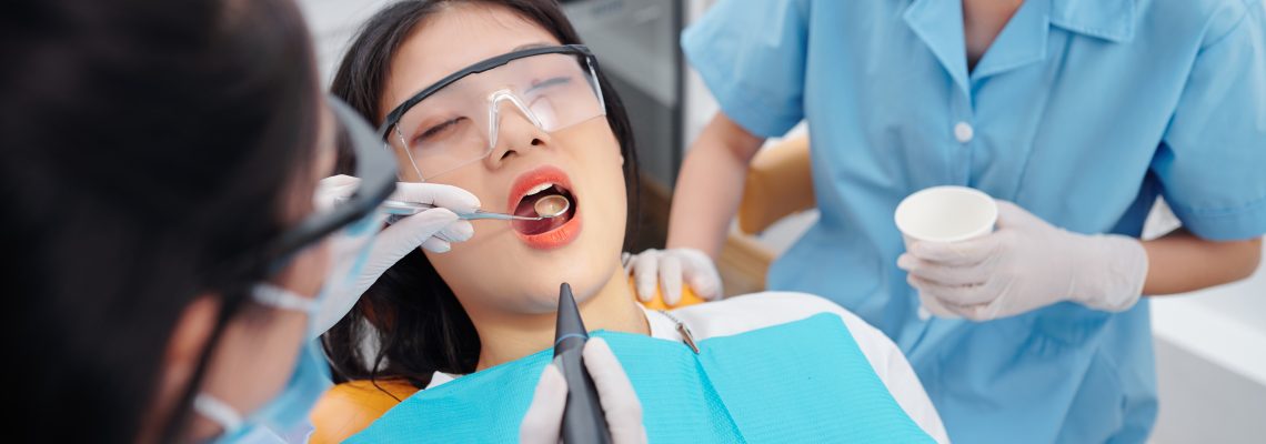 Dentist drilling teeth of young female patient suffering from teethache