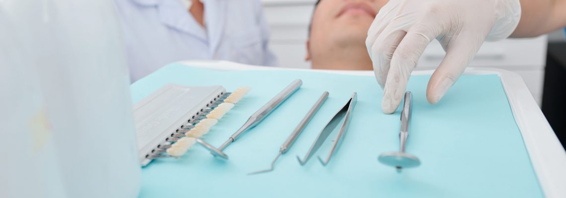 Dentist in silicone glove taking metal tools from tray when examining teeth of patients
