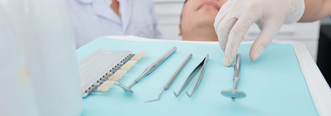Dentist in silicone glove taking metal tools from tray when examining teeth of patients