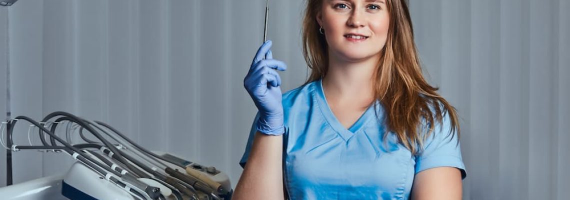 smiling-female-dentist-holding-dental-mirror-while-WHR396Q (1)